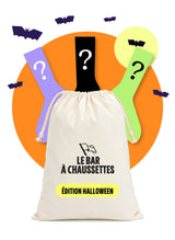 Lot surprise édition Halloween Le Bar à Chaussettes : un pochon en tissu et trois chaussettes à point d'interrogation devant un rond orange, avec une lune et des chauves-souris, sur fond blanc